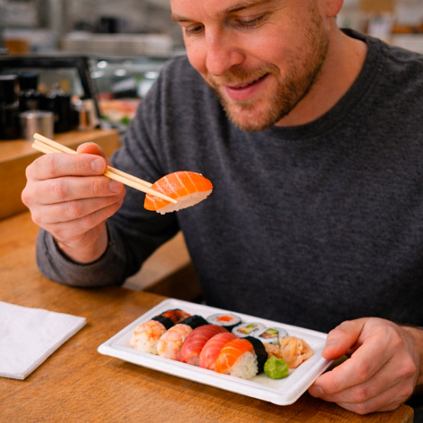 Una persona comiendo sushi en un restaurante en un plato de fibra