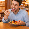 Hombre comiendo tortitas de un plato de palma