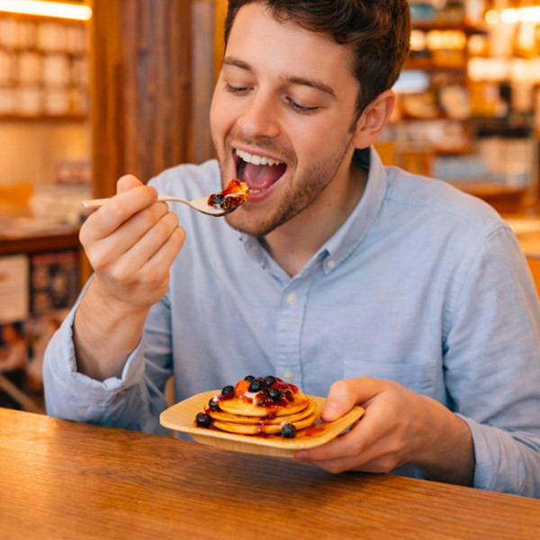 Hombre comiendo tortitas de un plato de palma