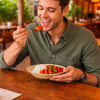 Hombre comiendo en un restaurante junto al mar