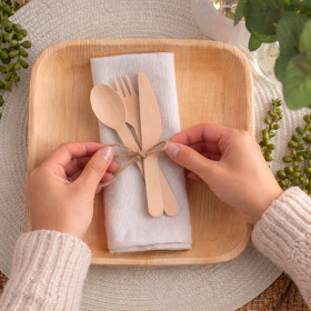 Servicio de mesa de madera en un plato de palma