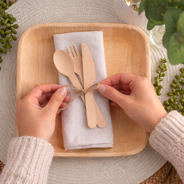 Servicio de mesa de madera en un plato de palma