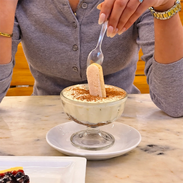 Mujer comiendo tiramisú con una cuchara de plástico