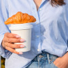 Café para llevar con tapa y croissant encima