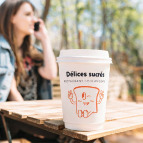Persona con bebida para llevar en vaso de papel personalizado con tapa