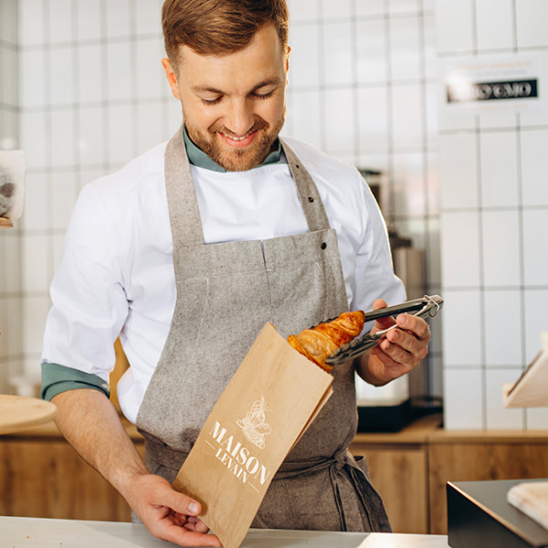 Boulanger envuelve los cruasanes en una bolsa kraft personalizada