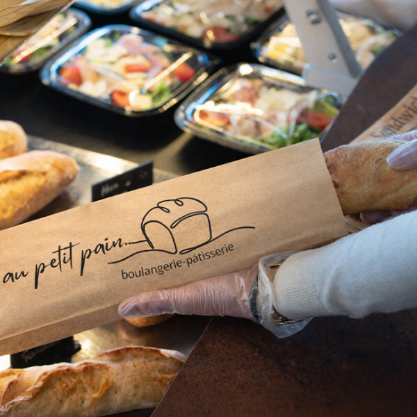 Bolsa personalizada para bocadillos: una dependienta envuelve un bocadillo en una panadería