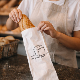 Vendedora envolviendo una baguette en una bolsita personalizada