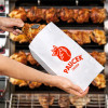 Nadie envuelve un pollo en una bolsa de papel personalizada en un asador